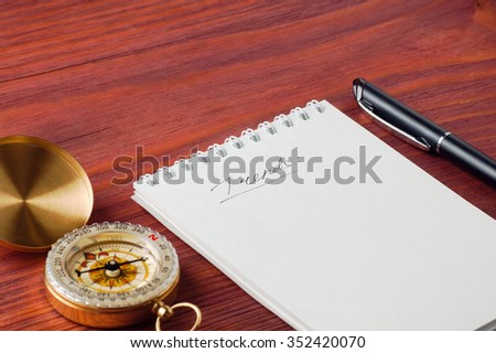 Closeup of notepad with handwritten word Trends, pen and compass nearby on wooden board shallow depth of field