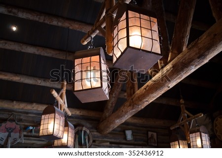 Old lantern are hanging under the ceiling with beam.