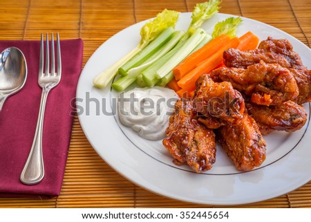 Tasty plate of glazed chicken wings with carrots, celery and dipping sauce.  Royalty-Free Stock Photo #352445654