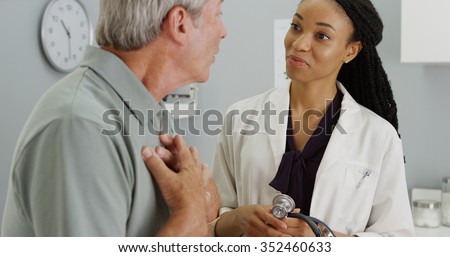 Black woman doctor listening to senior patient talking Royalty-Free Stock Photo #352460633