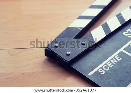 Vintage photo of crop and closeup movie clapper on wood.