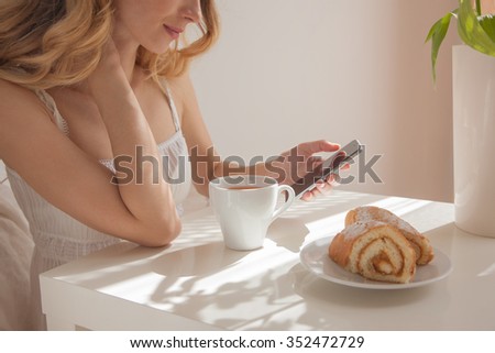 Composition cup of cappuccino and a roll cake, photography in the interior. Morning and phone. woman morning. Morning coffee. Pointing hand gesture     