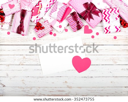 Wooden background with greeting carde and  pink gifts