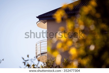 Villa in autumn, home with balcony in a suburb at fall on blue sky background