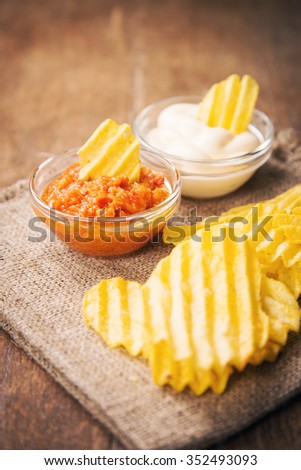 potato chips with mayonnaise and hot sauce on wooden background