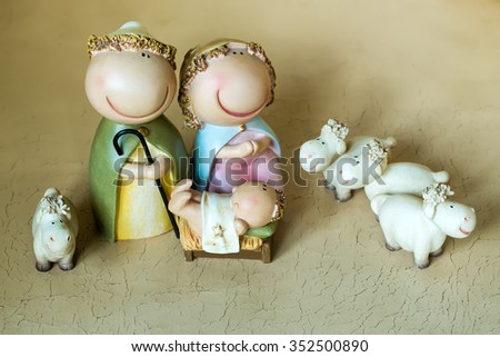 Closeup view of decorative celebrating Christmas and Jesus birth figurines of holy virgin Mary Joseph newborn child with few white sheeps standing on light leather background, horizontal picture