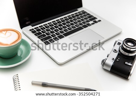 Laptop, vintage camera, cup of coffee, notepad and pen isolated over white background