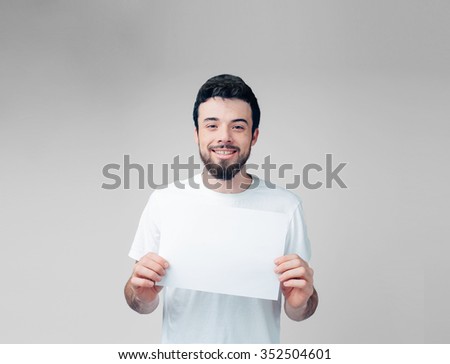 The bearded student in a white T-shirt holding a blank sheet of paper. 
