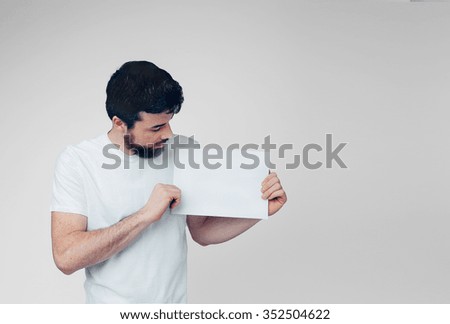 The bearded student in a white T-shirt holding a blank sheet of paper. 
