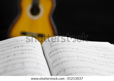 Musical chords and guitar on background in dark room