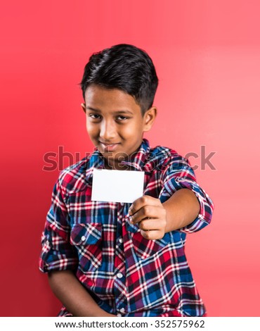 indian kid holding white card, indian boy and card, indian kid or indian boy with white card or banner, red background, smart boy, asian boy showing white empty card