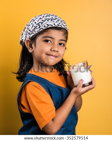 4 years old indian cute girl with a glass full of  plain milk - Kids and nutrition concept