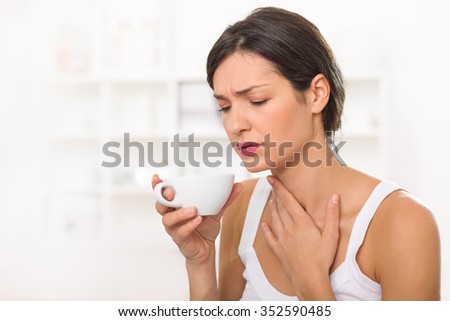 Young woman with a sore throat drinking tea Royalty-Free Stock Photo #352590485