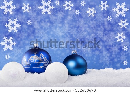 Blue Christmas balls in the snow with a blue background