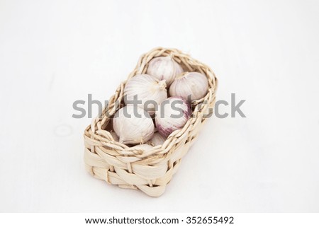 Delicious and organic chinese garlic in a basket on white wooden table, natural light, wooden table. Selective focus.