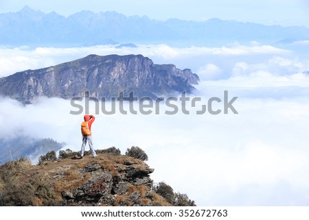 young woman photographer taking photo for beautiful landscape on mountain peak
