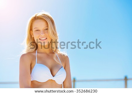 Portrait of young pretty woman in white bikini relaxing on sandy beach