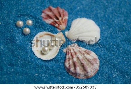 shells and pearls isolated on blue background made of little blue rocks 