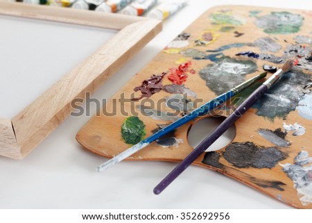 Art palette with paint, border and a brush on white background