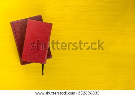 Top view of colorful hardback books on yellow background. Composition with vintage old hardback books, diary, fanned pages on wooden deck table. Books stacking. Back to school. Education background.