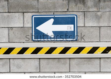 One-way sign and barricade tape on a cement wall in Japan