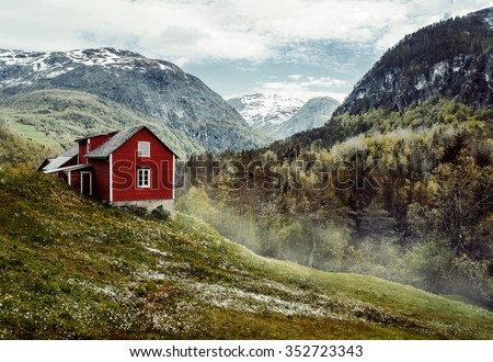 Wooden cottage in the valley. Flowers. Stone snowy mountains. Stalheim, Norway. Fog. Vintage Royalty-Free Stock Photo #352723343