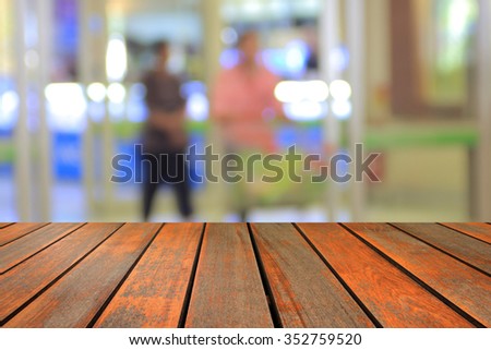 wood table and  abstract blurred photo of department store shopping mall center and people background