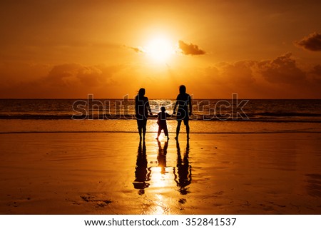 Happy family on a beach at sunrise with child mother and father