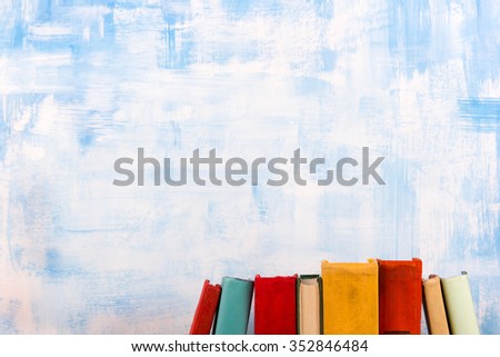 Composition with old vintage colorful hardback books, diary on wooden deck table and artistic blue background. Books stacking. Back to school. Copy Space. Education background