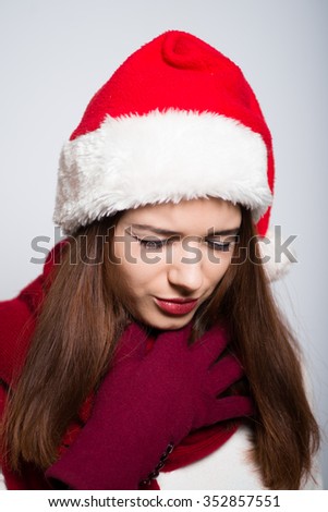 Christmas Girl has a sore throat, the common cold. Santa hat isolated portrait of a woman on a gray background.