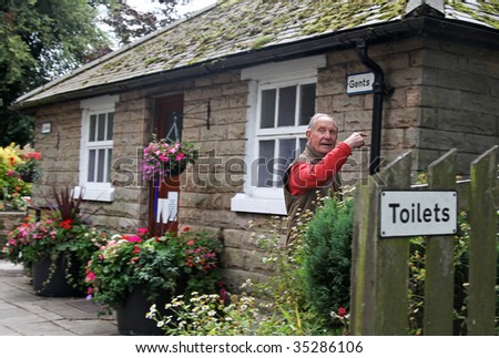 Caught short, elderly Gent dashes to pretty public Toilette in a small English Village. with some light motion blur