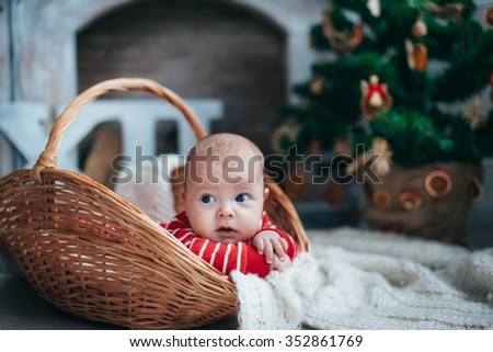 funny little boy lying in a basket on the background of the fireplace and Christmas tree