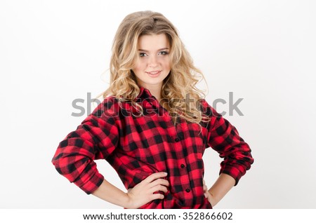 Angry young beautiful curly woman in checkered shirt c standing with arms akimbo