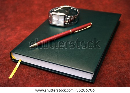 Agenda with red pen and wrist watch