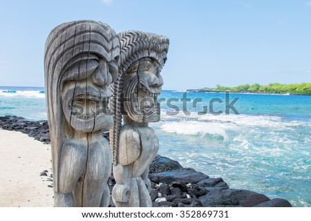 Ancient Polynesian style tiki wooden carvings along the beach greet visitors (tourists) to Ki'i Pu'uhonua O Honaunau National Park on the Big Island of Hawaii, an historic travel destination. Royalty-Free Stock Photo #352869731
