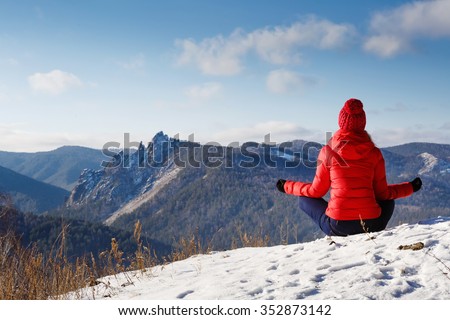 The young beautiful woman in mountains has a rest in the winter at the weekend, meditation, yoga Royalty-Free Stock Photo #352873142