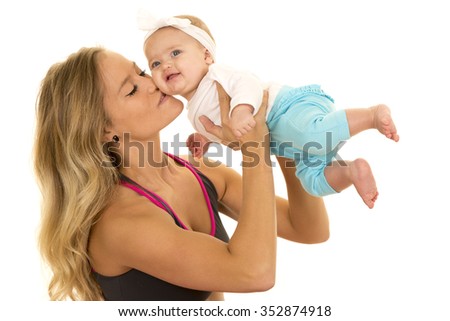 A woman in her fitness clothing kissing her baby girl on the cheek.