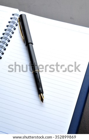 Notebook with fountain pen on wooden table