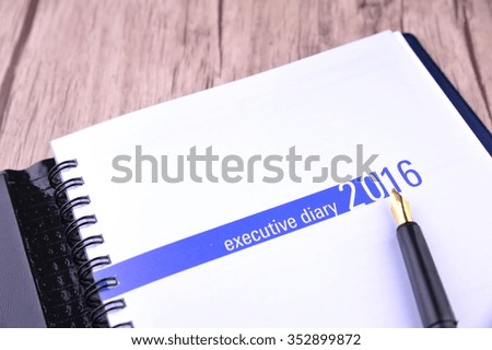 Executive diary with fountain pen on wooden table