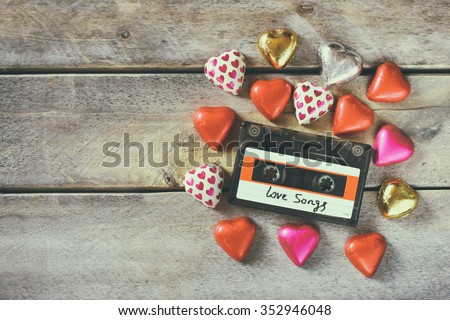 top view image of colorful heart shape chocolates and audio cassette on wooden table. valentine's day celebration concept. retro toned and filtered