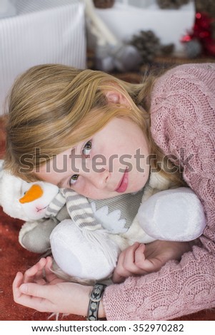 Pretty young girl dreaming of Christmas on top of a decorative gift