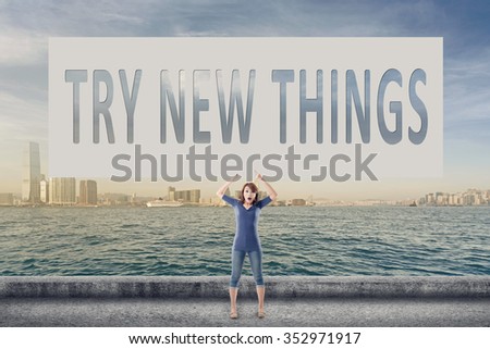 Try new things, words on blank board hold by a young girl in the outdoor.