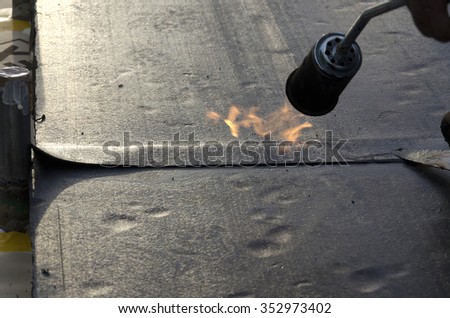 flame during welding of a waterproofing membrane on a roof Royalty-Free Stock Photo #352973402