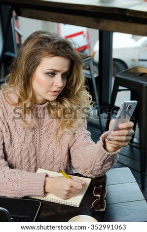 young beautiful woman reading sms on the phone in cafe