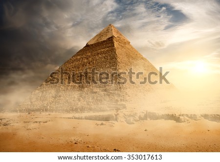 Pyramid in sand dust under gray clouds Royalty-Free Stock Photo #353017613
