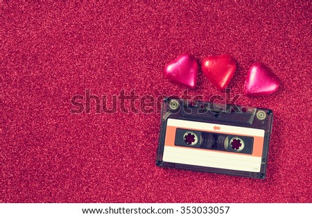 top view image of colorful heart shape chocolates and audio cassette on pink glitter background. valentine's day celebration concept