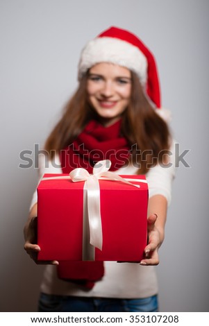 Christmas girl gives a gift. Santa hat isolated portrait of a woman on a gray background.