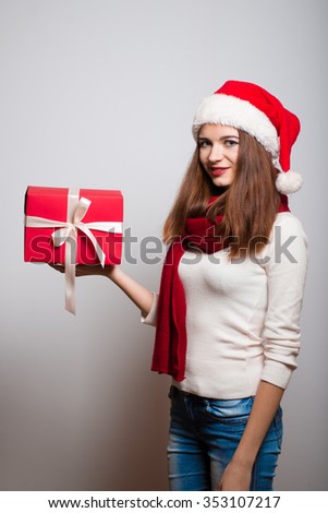 Christmas girl gives a gift. Santa hat isolated portrait of a woman on a gray background.