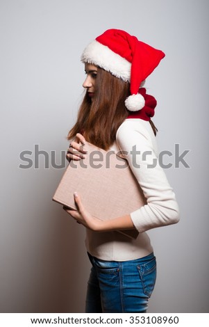 Christmas girl holding a book. Education. Santa hat isolated portrait of a woman on a gray background.