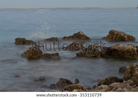 Evening sea waves on the shore among the stones in a long exposure